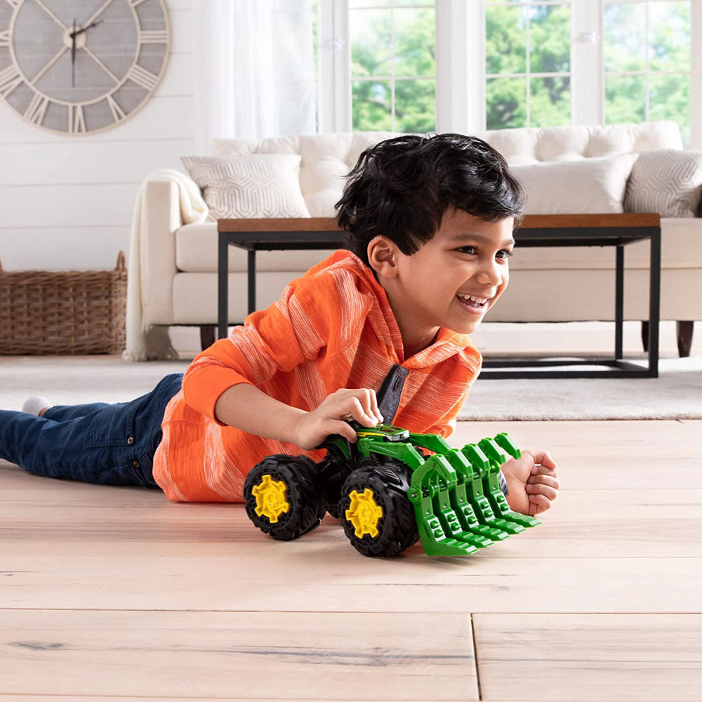 A boy is playing with the Monster Treads Rev Up Tractor Toy Vehicle by John Deere